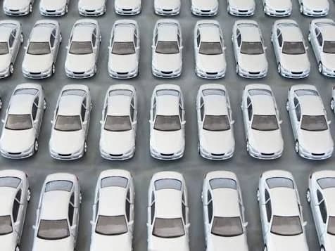 Rows of identical white cars filling a holding lot