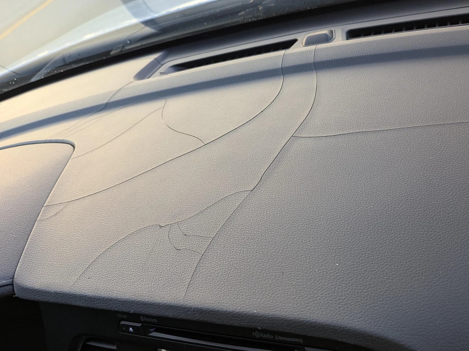 A dashboard split by a network of cracks after years of sun through the windshield