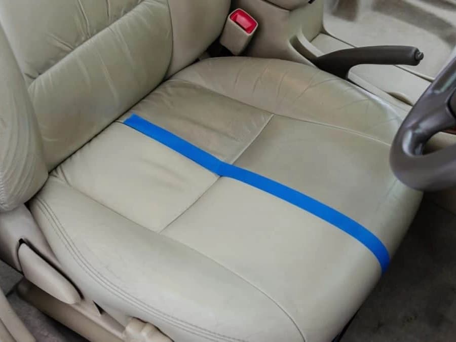 A cream leather seat masked down the middle: the restored half back to an even colour, the untouched half still dulled and soiled