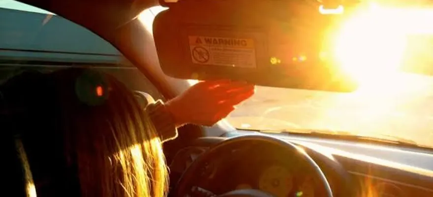 Driver squinting into low sun coming under the visor