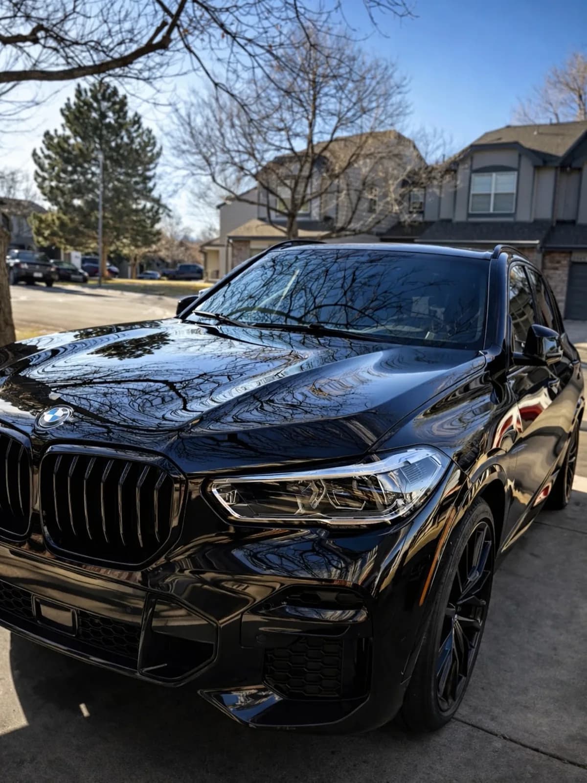 A coated black BMW X5 reflecting its surroundings like a mirror