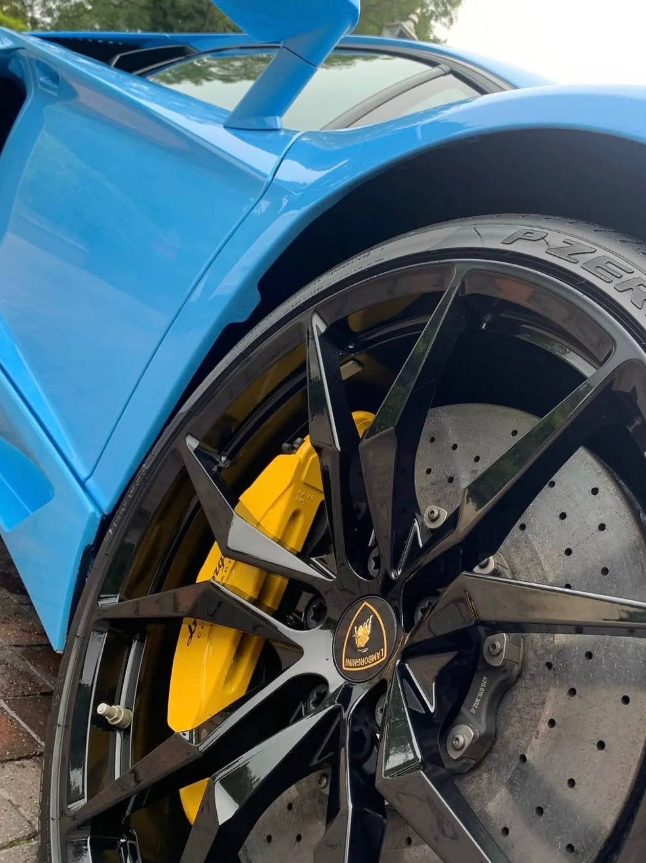 A coated wheel and yellow brake caliper on a Lamborghini Huracán, clear of brake dust