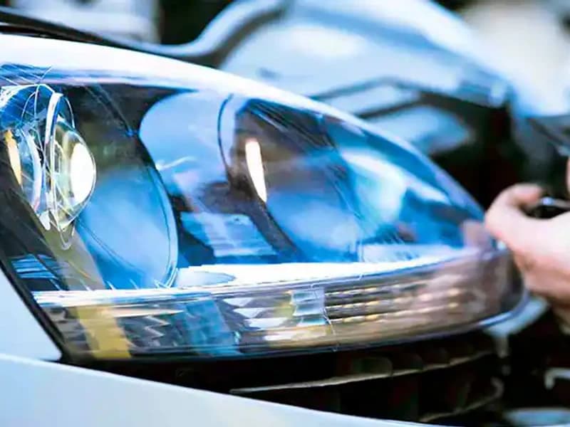 A hand working product across a clear headlight lens